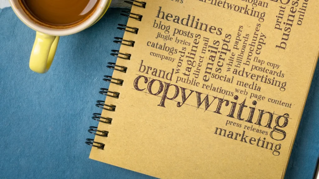 A notepad with words like 'copywriting,' 'headlines,' 'blog posts,' 'brand,' and 'marketing' printed on it, beside a spilled cup of coffee, symbolizing creative content creation.